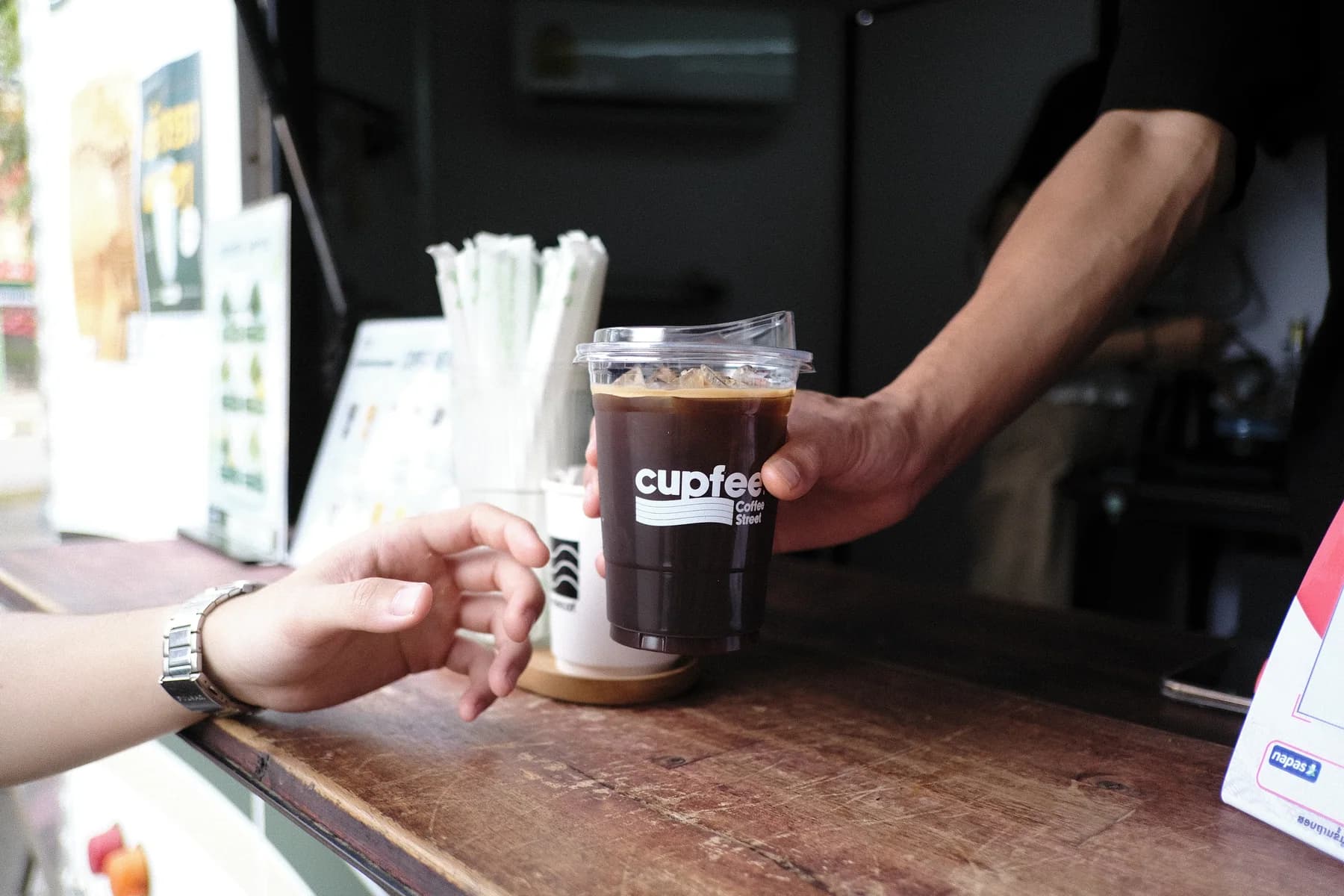 A fresh iced Cupfee coffee being handed to a customer